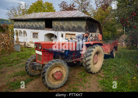 Landwirt mit einem Traktor mit Anhänger durch seinen Hinterhof orchard Stockfoto