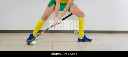 Schöne junge Frau mit Hockey Stick und die Kugel gegen den weißen Hintergrund Stockfoto