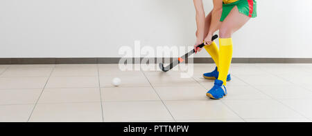 Schöne junge Frau mit Hockey Stick und die Kugel gegen den weißen Hintergrund Stockfoto