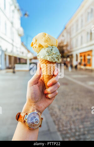 Frau mit grünen Pistazien und gelbe Melone Eistüte in der Hand Stockfoto