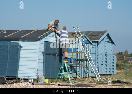 Zwei Männer arbeiten, Reparaturen auf dem Dach einer Strandhütte Stockfoto