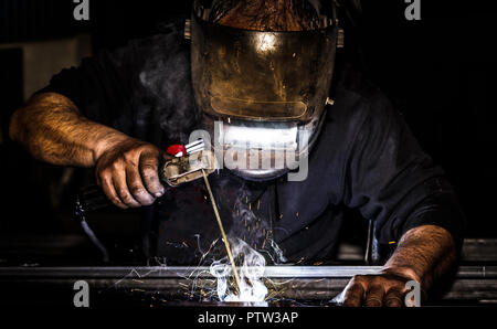 Close up Hochformat von professionellen Maske geschützt Schweißer Mann schweißen Metall- und Funken Metall. Stockfoto