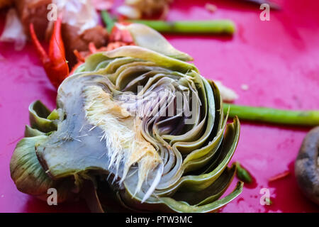 Gekochte Artischocke in der Hälfte liegen auf rosa Tischdecke mit Pilzen und Spargel an panzerkrebsblutgeschwür-selektiven Fokus Stockfoto