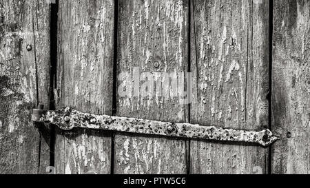 Alten rustikalen Wicket in Schwarz und Weiß. Gestreifte Holz- Textur. Künstlerische close-up vintage Holz Tür und rostiges Metall Scharnier. Zusammenfassung Hintergrund. Stockfoto