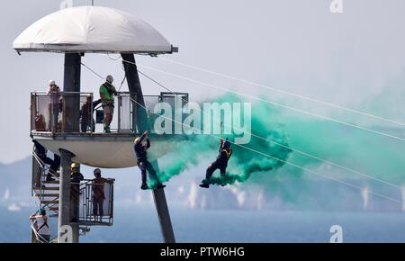 Zwei Mitglieder des Tiger Freefall Fallschirm display Team erleben den Nervenkitzel des Weltersten Pier Drahtseil in Bournemouth zu Ufer Stockfoto