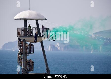 Zwei Mitglieder des Tiger Freefall Fallschirm display Team erleben den Nervenkitzel des Weltersten Pier Drahtseil in Bournemouth zu Ufer Stockfoto