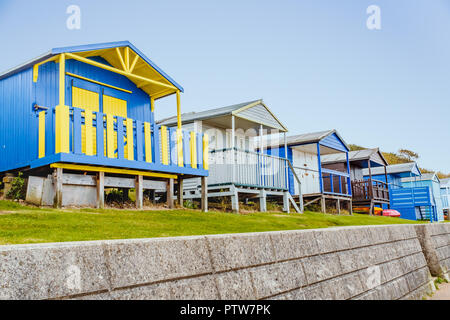 Uriges Holz- Bungalows in einer Reihe entlang ein Gras kurz oberhalb einer Steinmauer in Tankerton, Whitstable, Kent, Großbritannien Stockfoto