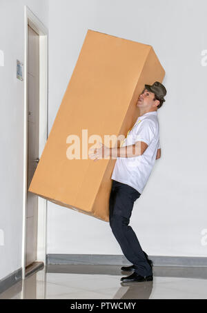 Der Postbote trägt ein grosses Paket. Der E-Mail-Dienst trägt eine große Lieferung in die Wohnung. Stockfoto