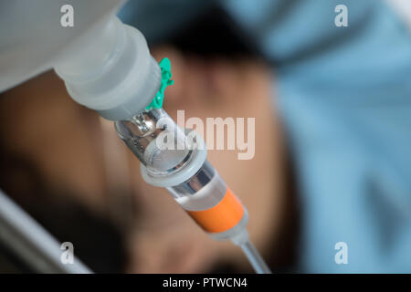 Close up Kochsalzlösung Tropfen mit einem Patienten liegen auf einem Bett im Hintergrund. Stockfoto