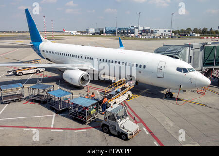 Flugzeug steht auf einer Start- und Landebahn und entlädt Gepäck. Flugzeuge Vorbereitung auf dem Flughafen. Stockfoto