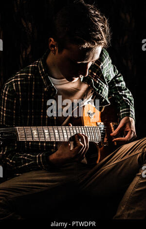 Linkshänder Männliche Jugendlich Musiker spielt E-Gitarre, mit ihm auf seinen Schoß. Stockfoto