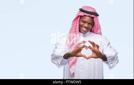 Junge arabische afrikanischen Mann mit traditionellen Kufiya über isolierte Hintergrund in der Liebe mit Herz und mit Hand lächelnd. Romantische con Stockfoto