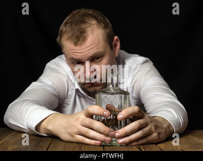 Junge Mann sieht eine Flasche mit Alkohol, traurig, nachdenklich, Probleme, männliche Alkoholismus Stockfoto