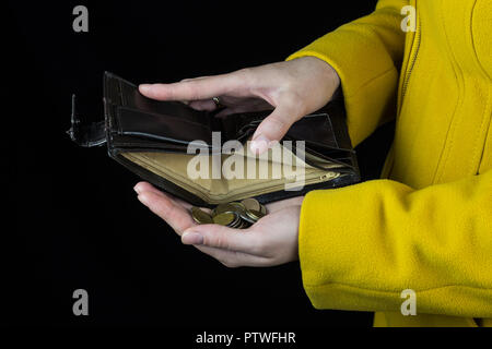 Mädchen gießen Münzen aus einer Handtasche, schwarz, Hintergrund, Nahaufnahme, Münze Stockfoto