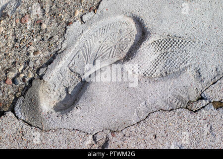 Der Fußabdruck eines Sportschuh in konkreten eingeprägt. Ein Abdruck des Schuhs für immer in den Bürgersteig. Jahreszeit der Herbst. Stockfoto