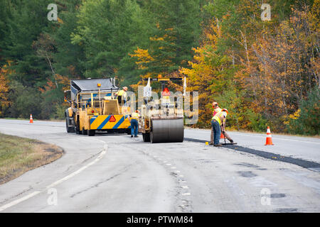 Ein Projekt für die Instandhaltung der Straßen in den Adirondack Mountains, NY USA mit einem Dump Truck, ein Pflasterstein, einer Rolle und einem Bau-Crew. Stockfoto