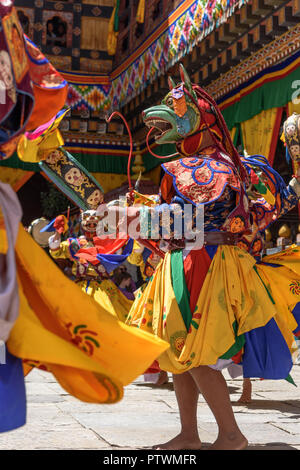 Buddhistischer Mönch tanzen und Halten einer an farbenfrohen Maskentanz im jährlichen Buddhismus Paro Tsechu Festival in Bhutan Kloster Tempel in der Trommel. Stockfoto