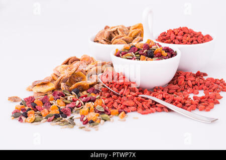 Getrocknete Früchte, Beeren und Samen in Schalen auf grauem Hintergrund. Stockfoto