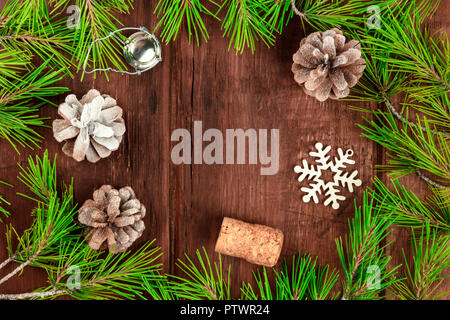 Weihnachten Hintergrund mit Fir Tree Branches, Kegel, Schnee, Weihnachten Dekorationen und ein Korken, auf einem dunklen rustikalen Textur mit Kopie Raum Stockfoto