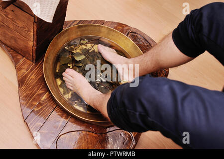 Männer Füße Pediküre Badewanne mit Eichenlaub. Fuß- und Nagelpflege Stockfoto