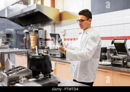 Koch Kochen mit Tablet-pc im Restaurantküche Stockfoto