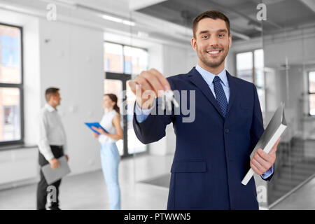 Lächelnd Realtor mit Schlüssel und Ordner im neuen Büro Stockfoto