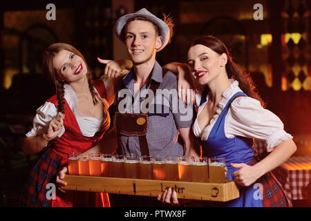 Menschen in bayerischen Kleidung mit einem Bier board und Gläser gegen einen Pub Hintergrund bei der Feier des Oktoberfestes Stockfoto