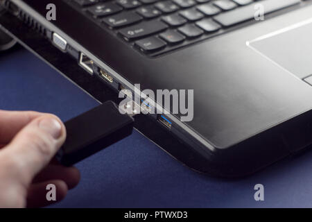 Hand fügt ein Mann ein USB-Flashlaufwerk an einem Laptop Stockfoto