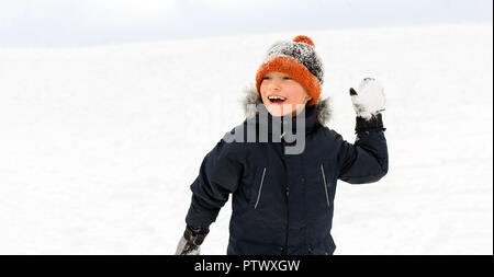 Glückliche junge spielt und wirft Schneeball im Winter Stockfoto