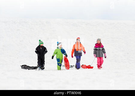 Gerne kleine Kinder mit Schlitten Rodeln im Winter Stockfoto