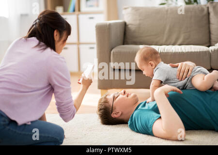 Mutter picturing Vater mit Baby von Smartphone Stockfoto