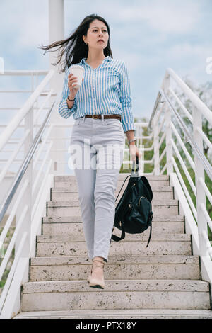 Ein Foto von einem zuversichtlich office Lady zu Fuß die Treppe hinunter nach der Arbeit Stockfoto