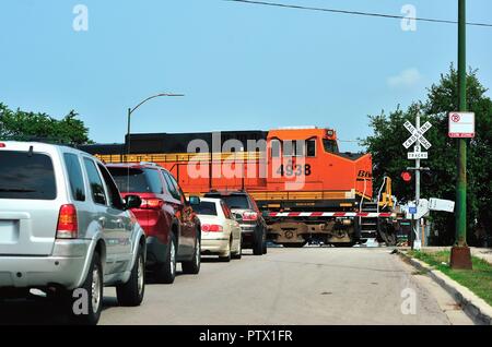 Chicago, Illinois, USA. Ein Burlington Northern Santa Fe Güterzug hält bis Verkehr, als es eine Straße in Chicago's Garfield Ridge Nachbarschaft kreuzt. Stockfoto