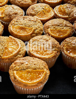 Orange und Mohn Muffins mit Orangenscheiben verziert. Stockfoto