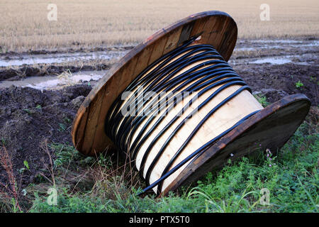 Fast leer Holz- Kabeltrommel in lehmigen Boden nach Regen. Stockfoto