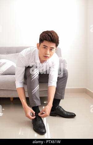 Der Mann die Hände binden Schuhbändern an seine neuen Schuhe. Menschen, Business, Fashion und Schuhe Konzept - Nahaufnahme der Mann Bein und die Hände binden Schnürsenkel. Stockfoto