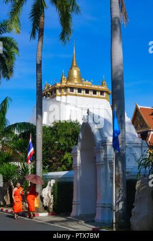 Buddhistische Mönche im weitläufigen Gelände des Wat Saket, Bangkok, Thailand, mit dem ikonischen Goldenen Berg (Phukhao Thong) im Hintergrund Stockfoto