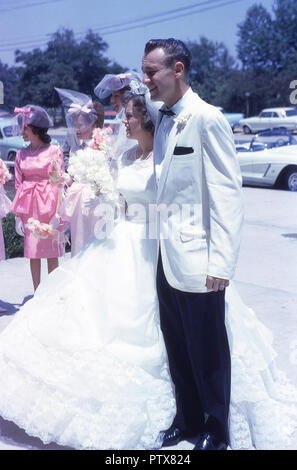 1962, historische, Hochzeit, Kalifornien, einem hellen, sonnigen Tag und die strahlende Braut und Bräutigam in ihre Hochzeit Ausstattungen zusammen draußen für ein Foto, USA stand. Stockfoto