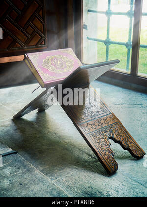 Der Koran, das heilige Buch des Islam, über einen Stand aus Holz, in einem Strahl der göttlichen Licht eingehüllt. Stockfoto