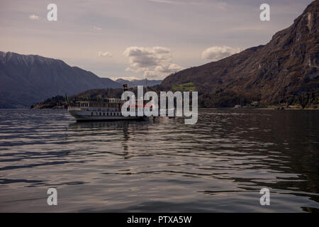 Menaggio, Italy-April 2, 2018: Concordia Fähre auf dem Comer see Leute transportieren mit Berg im Hintergrund Stockfoto