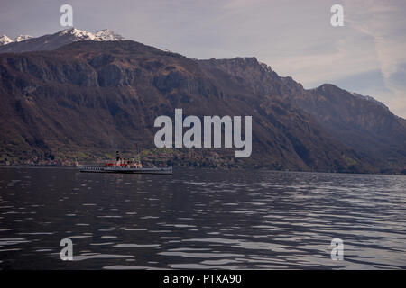 Menaggio, Italy-April 2, 2018: Concordia Fähre auf dem Comer see Leute transportieren mit Berg im Hintergrund Stockfoto