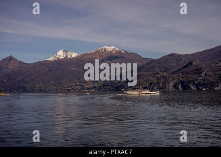 Menaggio, Italy-April 2, 2018: Concordia Fähre auf dem Comer see Leute transportieren mit Berg im Hintergrund Stockfoto