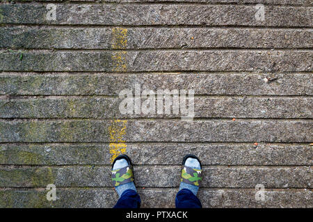Socked Slippered Füße auf Steinboden Stockfoto
