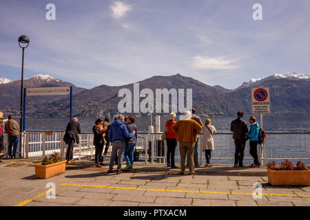 Menaggio, Italy-April 2, 2018: die Gruppe von Menschen und Touristen über den Comer See mit Berg im Hintergrund suchen Stockfoto