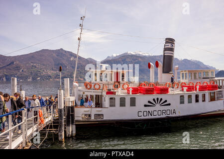 Menaggio, Italy-April 2, 2018: Concordia Fähre auf dem Comer see Leute transportieren mit Berg im Hintergrund Stockfoto