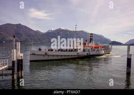 Menaggio, Italy-April 2, 2018: Concordia Fähre auf dem Comer see Leute transportieren mit Berg im Hintergrund Stockfoto