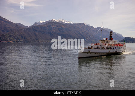 Menaggio, Italy-April 2, 2018: Concordia Fähre auf dem Comer see Leute transportieren mit Berg im Hintergrund Stockfoto