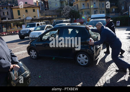 Menaggio, Italy-April 2, 2018: Die Menschen schieben eines aufgeschlüsselt Toyota Auto, Lombardei Stockfoto