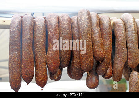 Würstchen. Würstchen hängen im Freien zum Verkauf auf einem Straßenmarkt. Hausgemachte Fleisch salami Wurst am Markt hängen in Zeile unter Sonnenlicht gut zu bilden Stockfoto