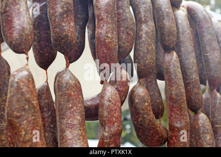 Würstchen. Würstchen hängen im Freien zum Verkauf auf einem Straßenmarkt. Hausgemachte Fleisch salami Wurst am Markt hängen in Zeile unter Sonnenlicht gut zu bilden Stockfoto